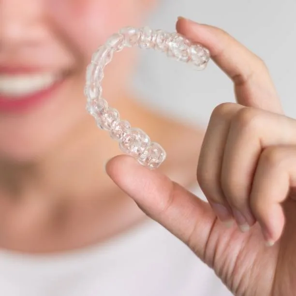 Hand holding an Invisalign clear aligner